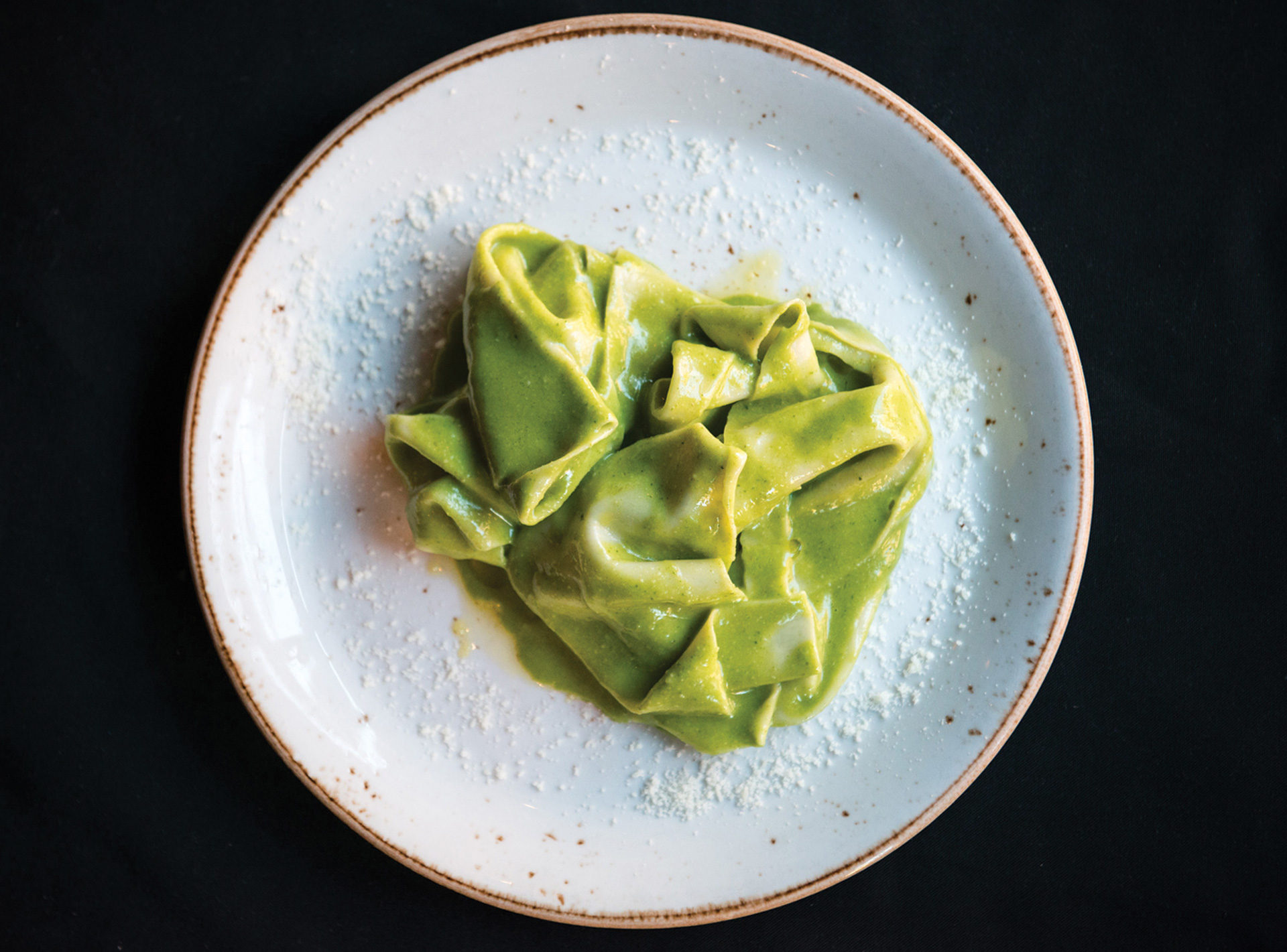 Top angle close up of our Mandilli di Seta, pillowy housemade hankerchief pasta, covered in delectable ligurian almond basil pesto